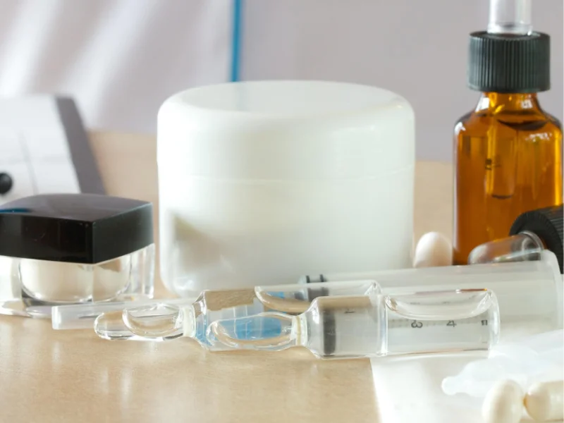 cremes, séruns, suplementos e injeções de ácido hialurónico pousados numa mesa - produtos com A.H
